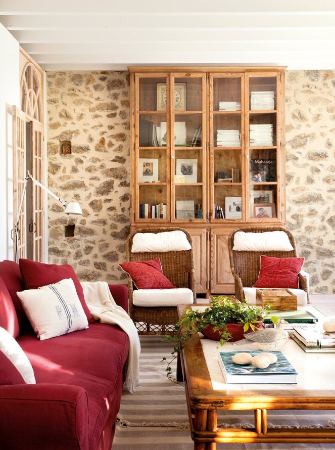salon_con_pared_de_piedra_libreria_antigua_y_sofa_rojo_953x1280